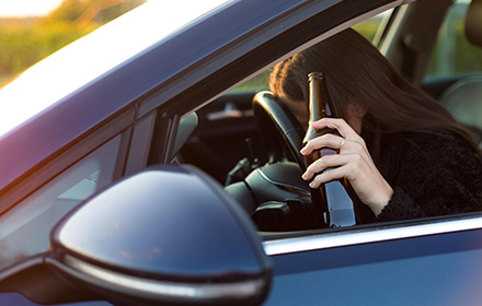 DUI Suspect Holding Beer Bottle and Leaning on Steering Wheel