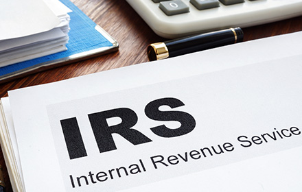 Magnifying Glass on IRS Logo To Represent the Identity Theft Crackdown