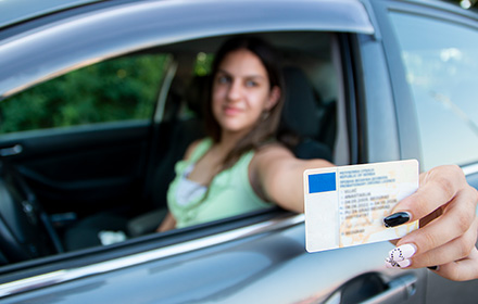 Young Woman Showing Fake Driver's License From Car Window