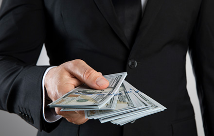 Close-up of Business Man Holding Wad of Cash to Represent White-Collar Crimes