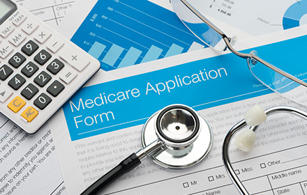 Calculator on Top of Medicare Application Form Representing Instances of Medicare Fraud