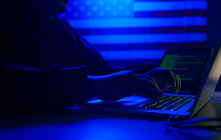 Person Comitting Cyber Crimes on a Laptop With U.S. Flag in the Background