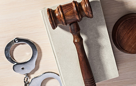 Judge Gavel, Law Book, and Handcuffs on Top of White Surface Representing the Consequences of Probation Violations